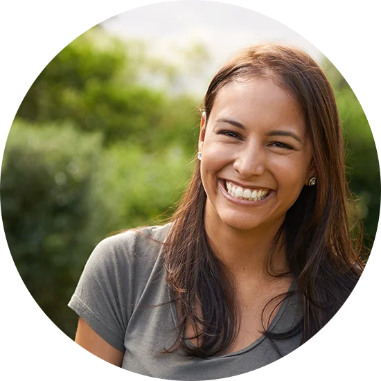 A woman smiles at the camera while standing outside. She is enjoying life after addiction treatment at Juniper Grove Recovery.