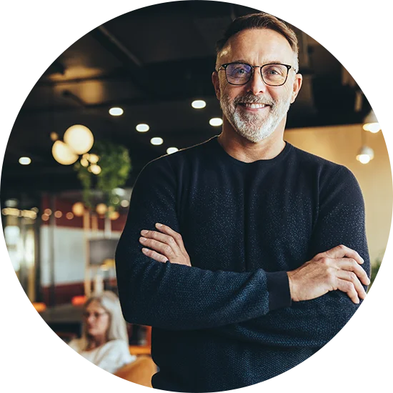 A man smiles with arms folded across his chest, looking directly at the camera. He's enjoying life after addiction treatment at Juniper Grove Recovery.