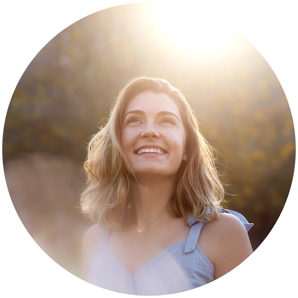 A young woman stands outside at dusk, staring up at the sky with a smile on her face. She is enjoying life after addiction treatment at Juniper Grove Recovery.