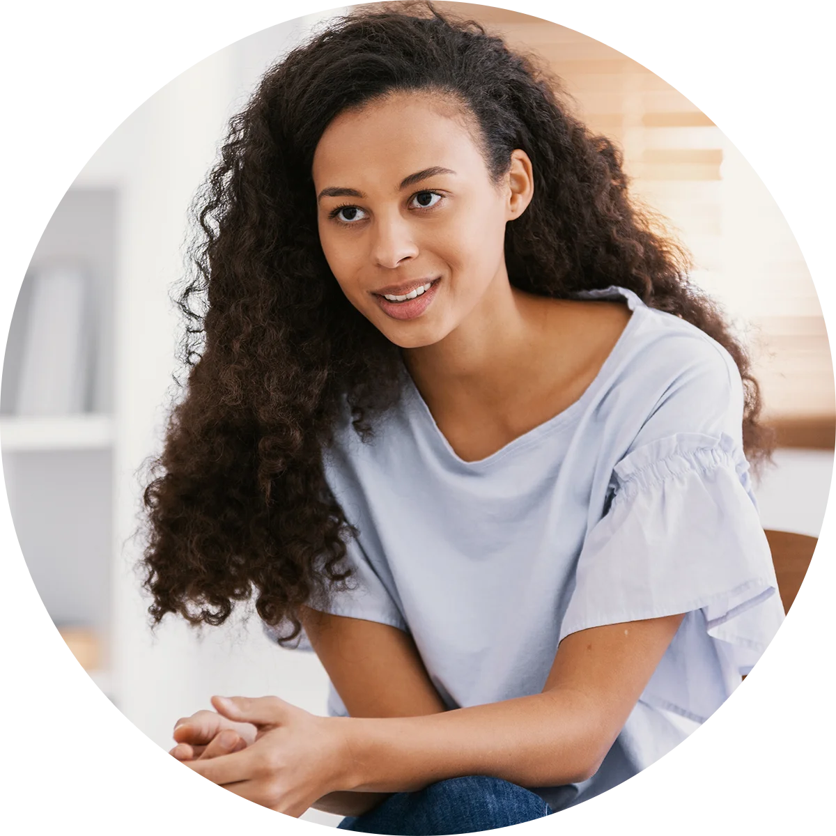 A young woman leans forward in conversation with a therapist while participating in addiction therapy at Juniper Grove Recovery.